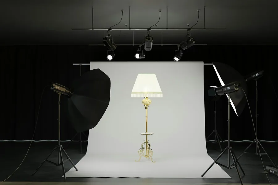Studiová lampa se softboxem postavená na stativu proti tmavému pozadí ateliéru